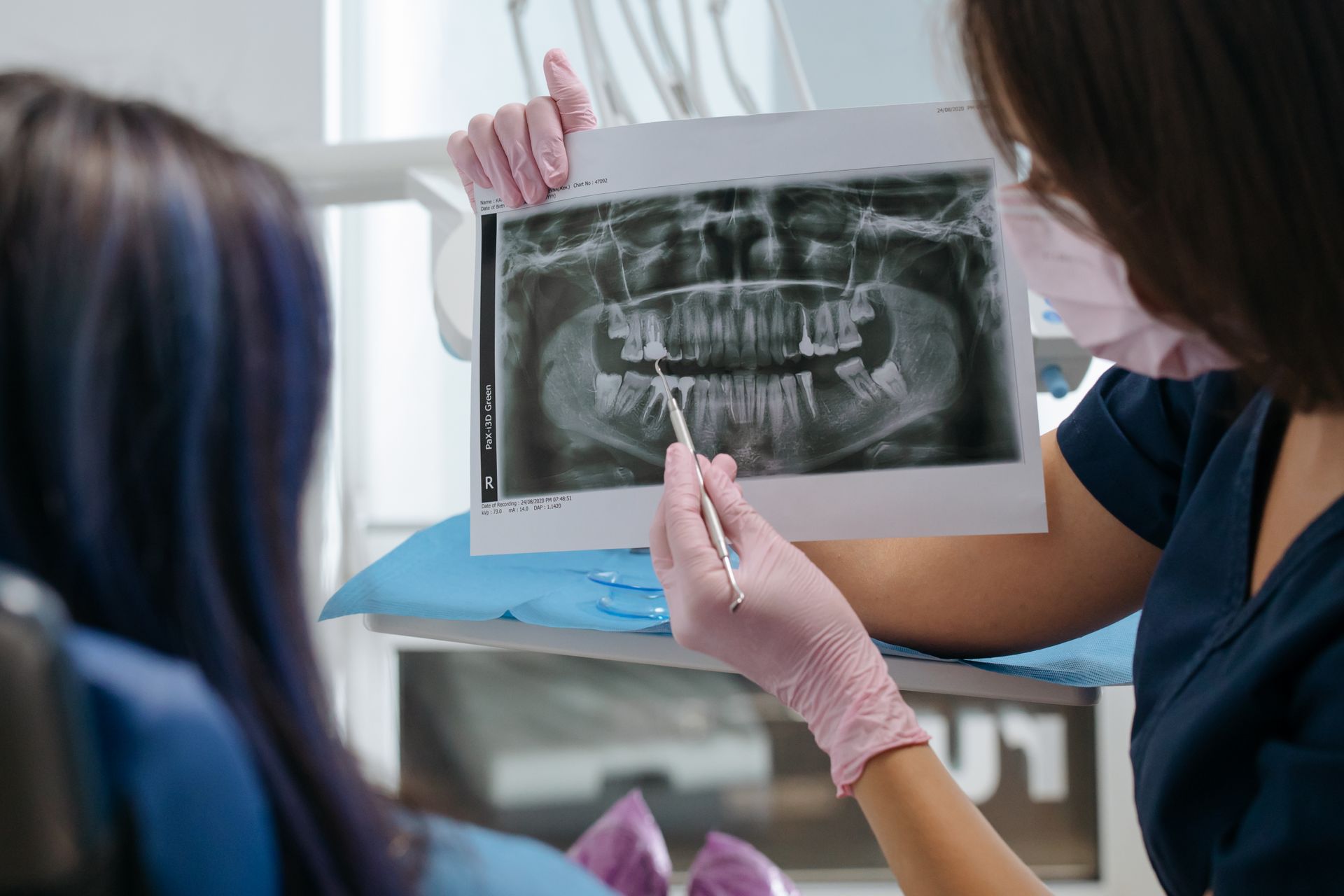Dentist reviewing a panoramic dental X-ray with a patient to check for an ankylosed tooth