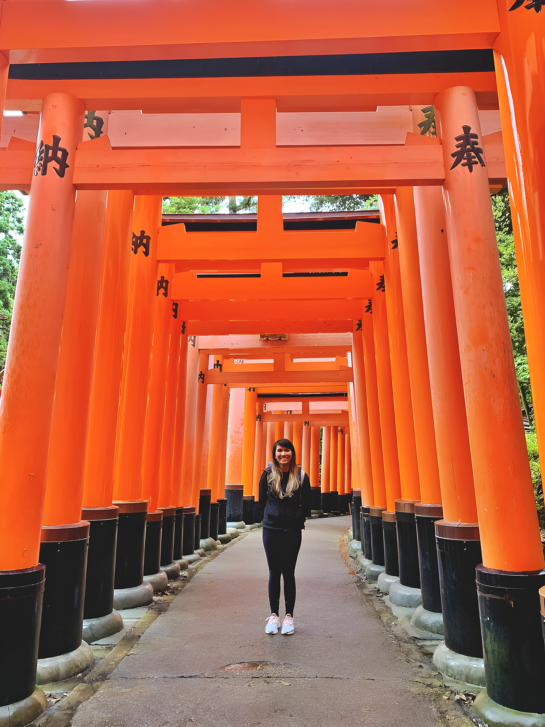 Dr. Gloria Luong walking the torii gate path at Fushimi Inari Shrine in Kyoto, Japan