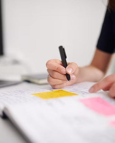Natalie Ecker schreibt mit schwarzem Stift auf Sticky Notes.