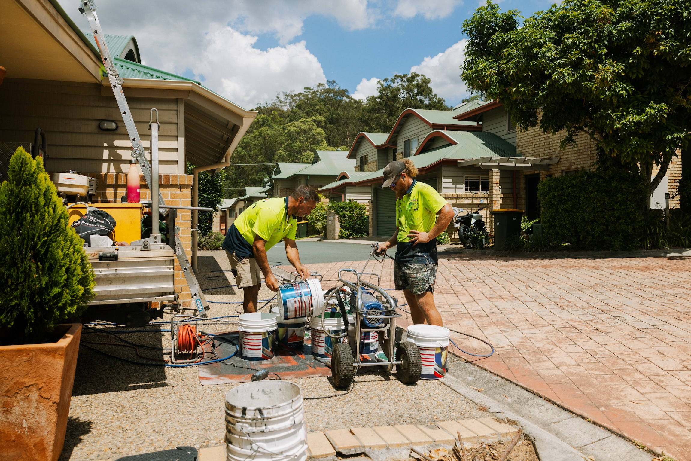 shieldcoat-brisbane.jpg	Mr Highlights Roofing team members preparing premium Shieldcoat roof paint using professional spray equipment on a driveway in a North Brisbane residential estate.