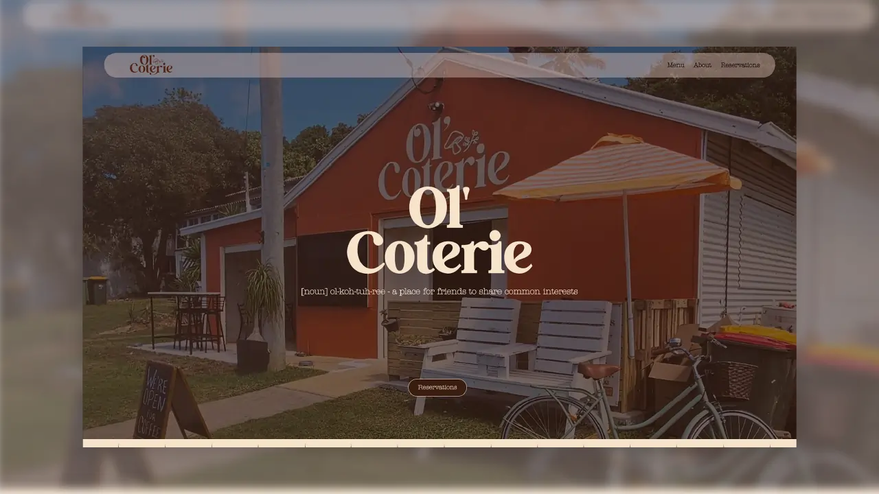 Outdoor view of Ol' Coterie coffee shop with orange building, bench, umbrella, and bicycle.