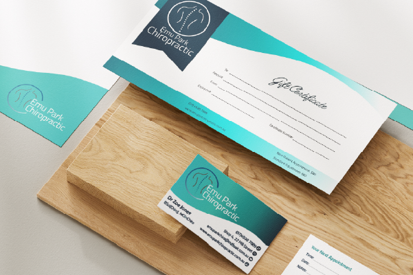 Emu Park Chiropractic gift certificate, business card, and appointment card on wooden board.