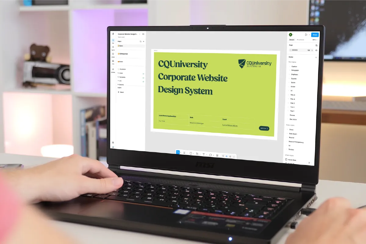 Person using a laptop displaying CQUniversity's Corporate Website Design System interface.