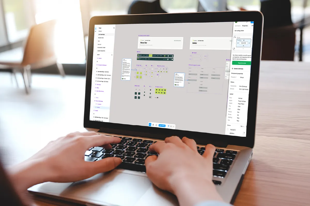 Person working on laptop showing a UI design and layout editor on screen.