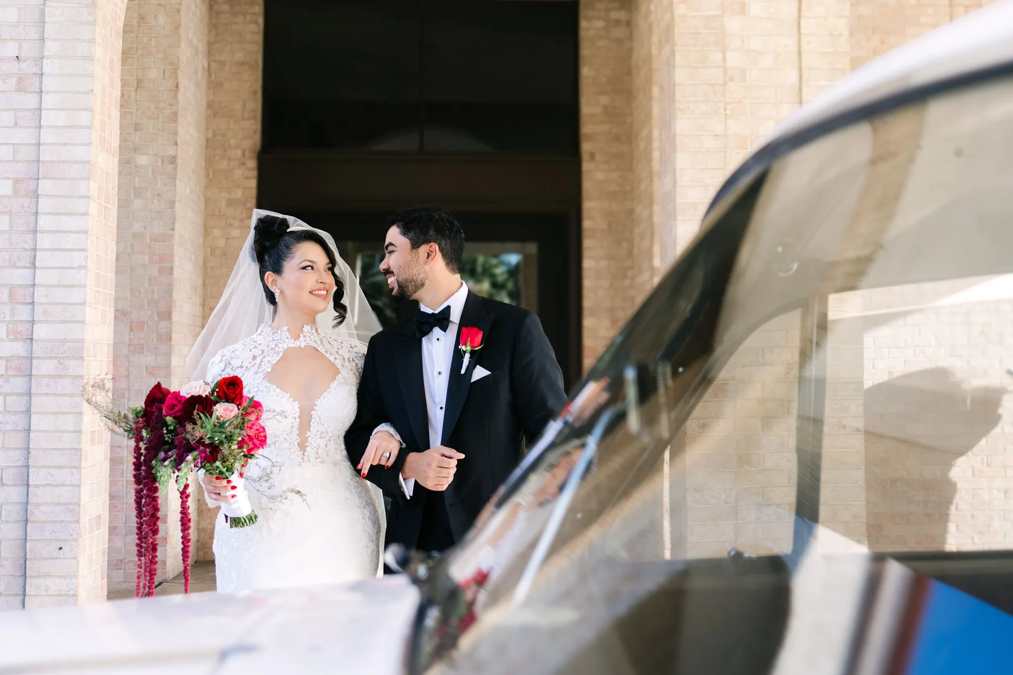 Bride and groom laughing together beside a classic car on their Austin Texas wedding day, documentary wedding photography by Moments By Marcela