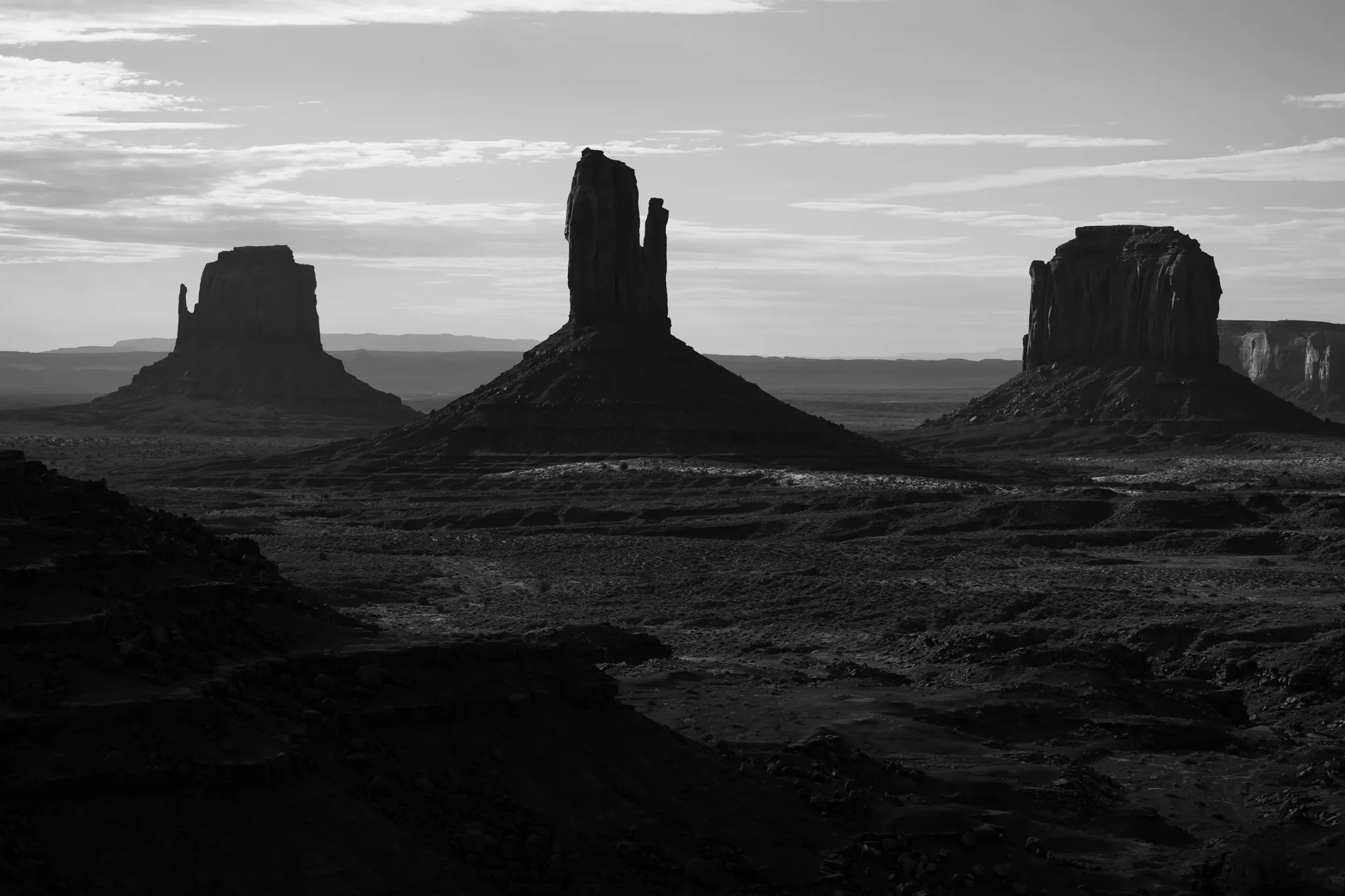 Documentary wedding photographer black and white landscape of Monument Valley buttes silhouetted against a moody sky
