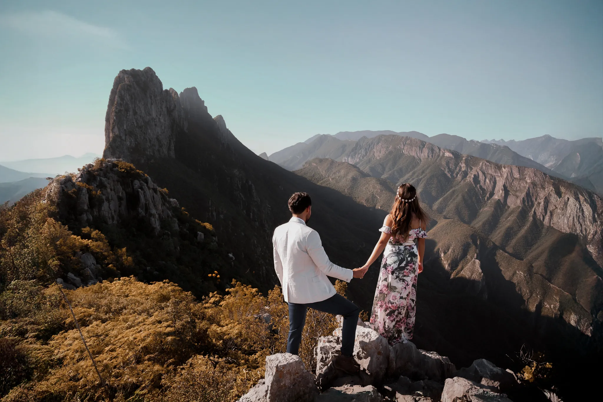 Documentary wedding photographer couple holding hands overlooking a dramatic mountain range at golden hour