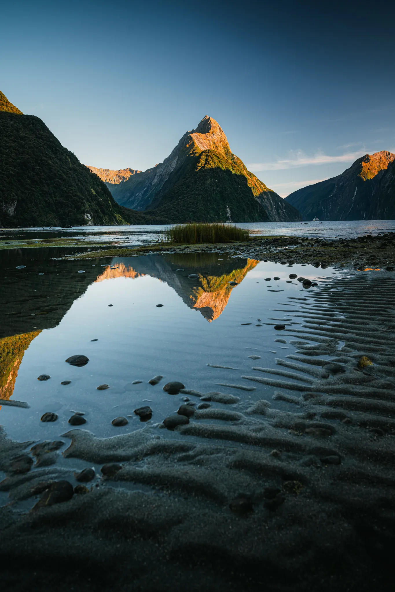 Documentary wedding photographer landscape of Mitre Peak reflected in a still tidal pool at Milford Sound New Zealand at golden hour