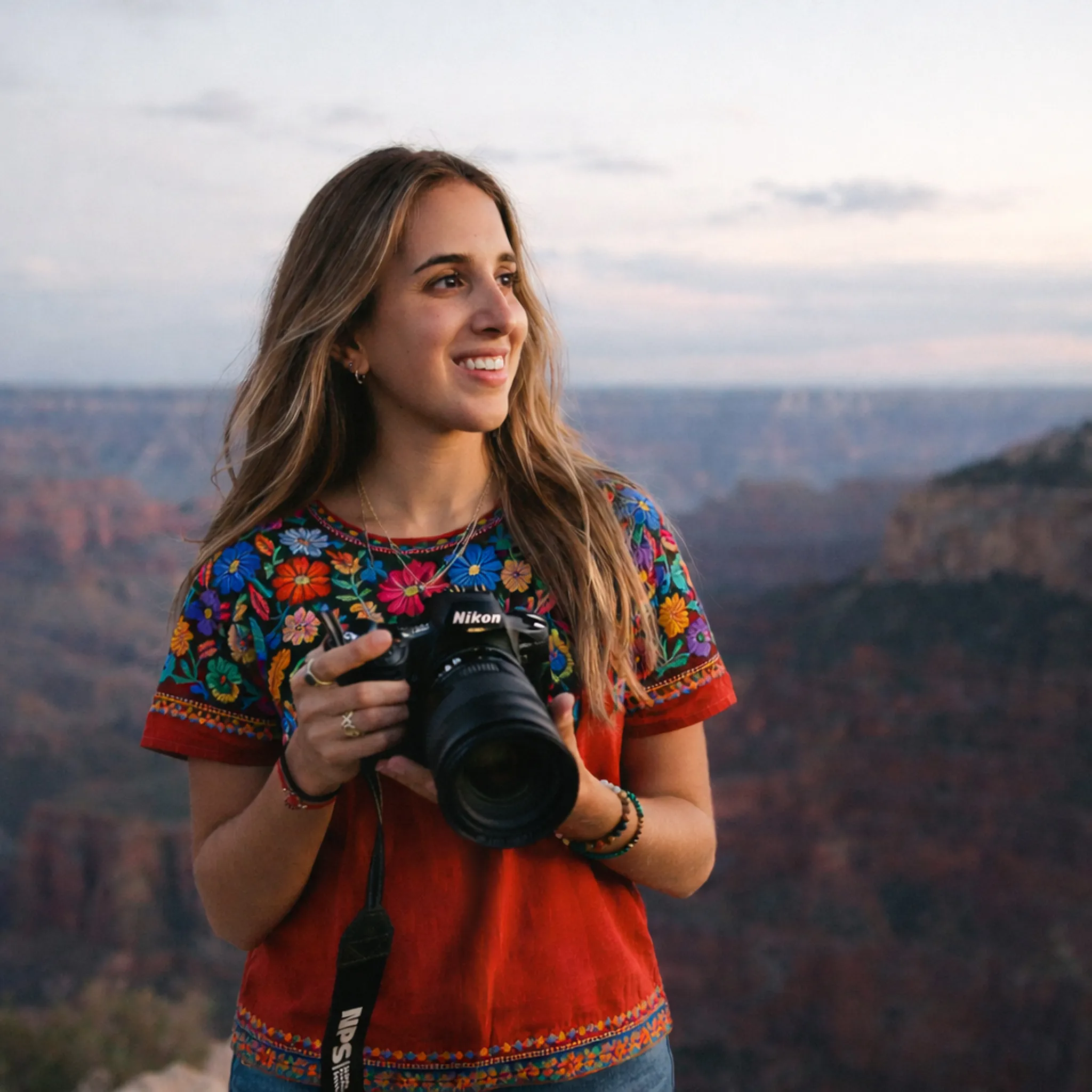 Documentary wedding photographer smiling with Nikon camera at the Grand Canyon at sunset
