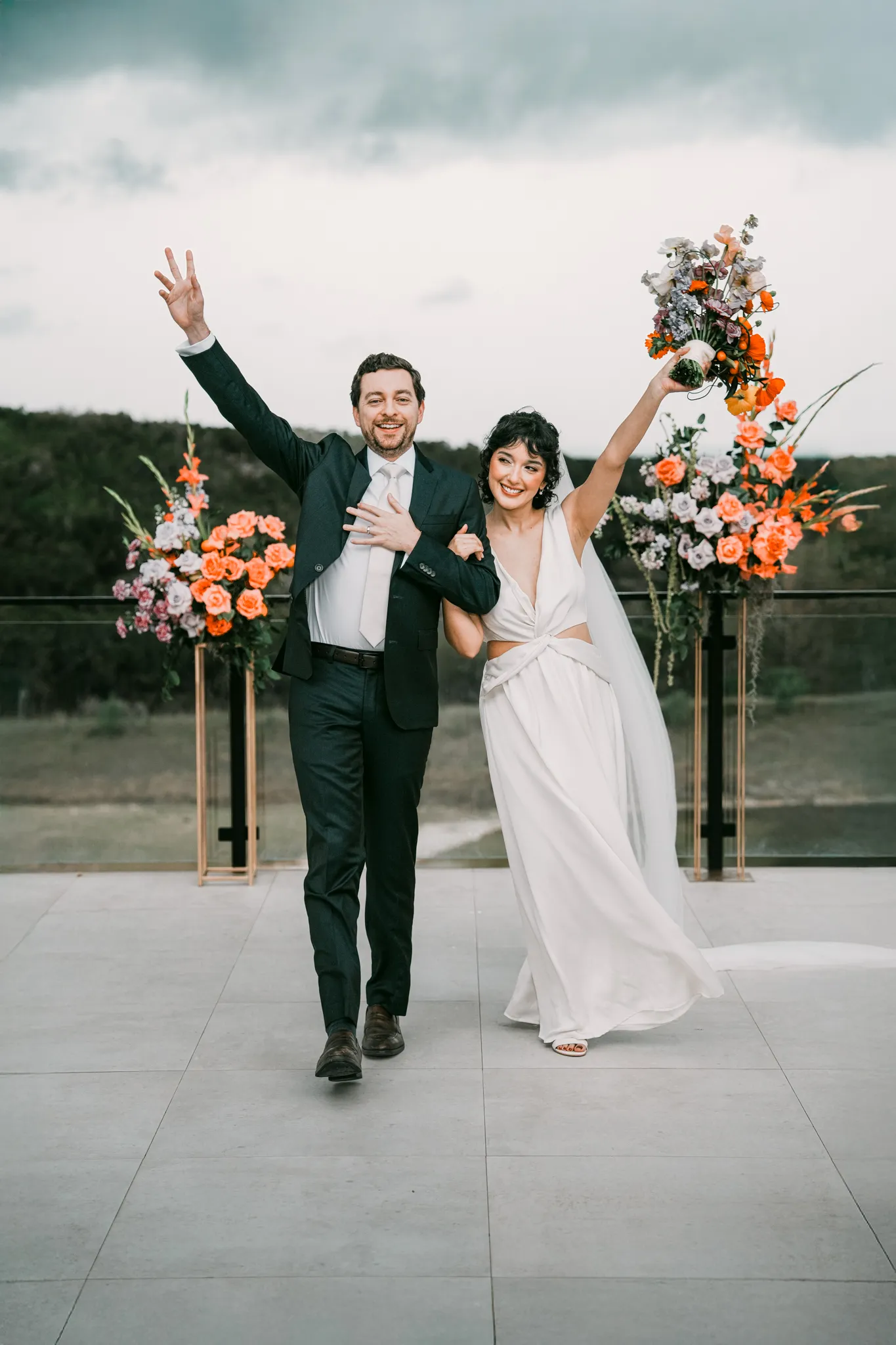 Austin Texas wedding photographer bride and groom celebrating with arms raised next to a colorful floral arrangement