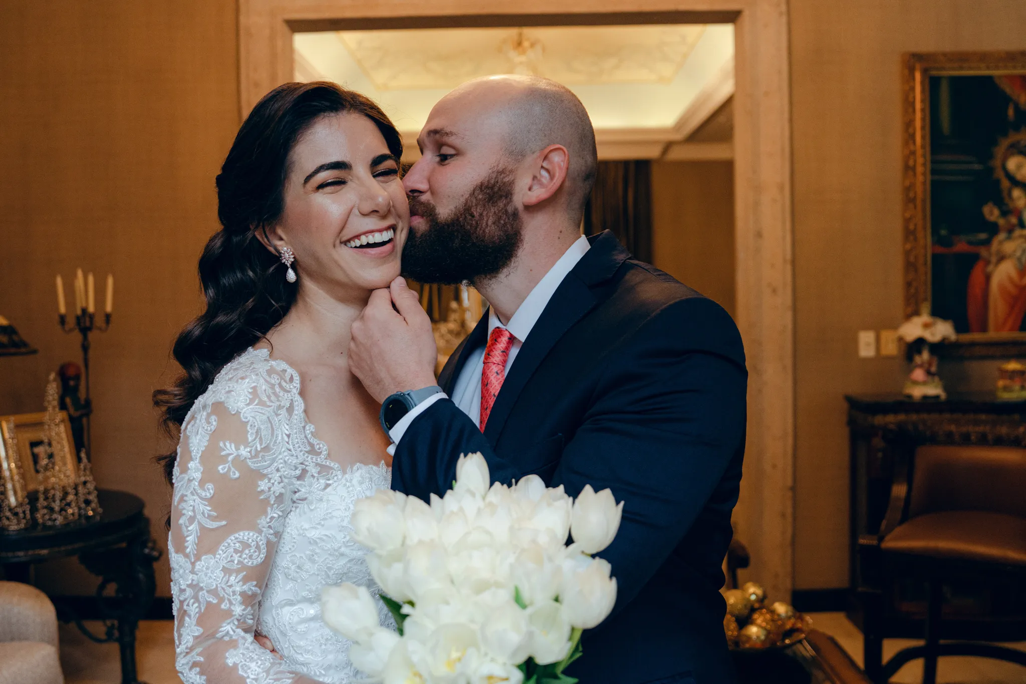 Bride laughing as groom kisses her cheek during wedding celebration