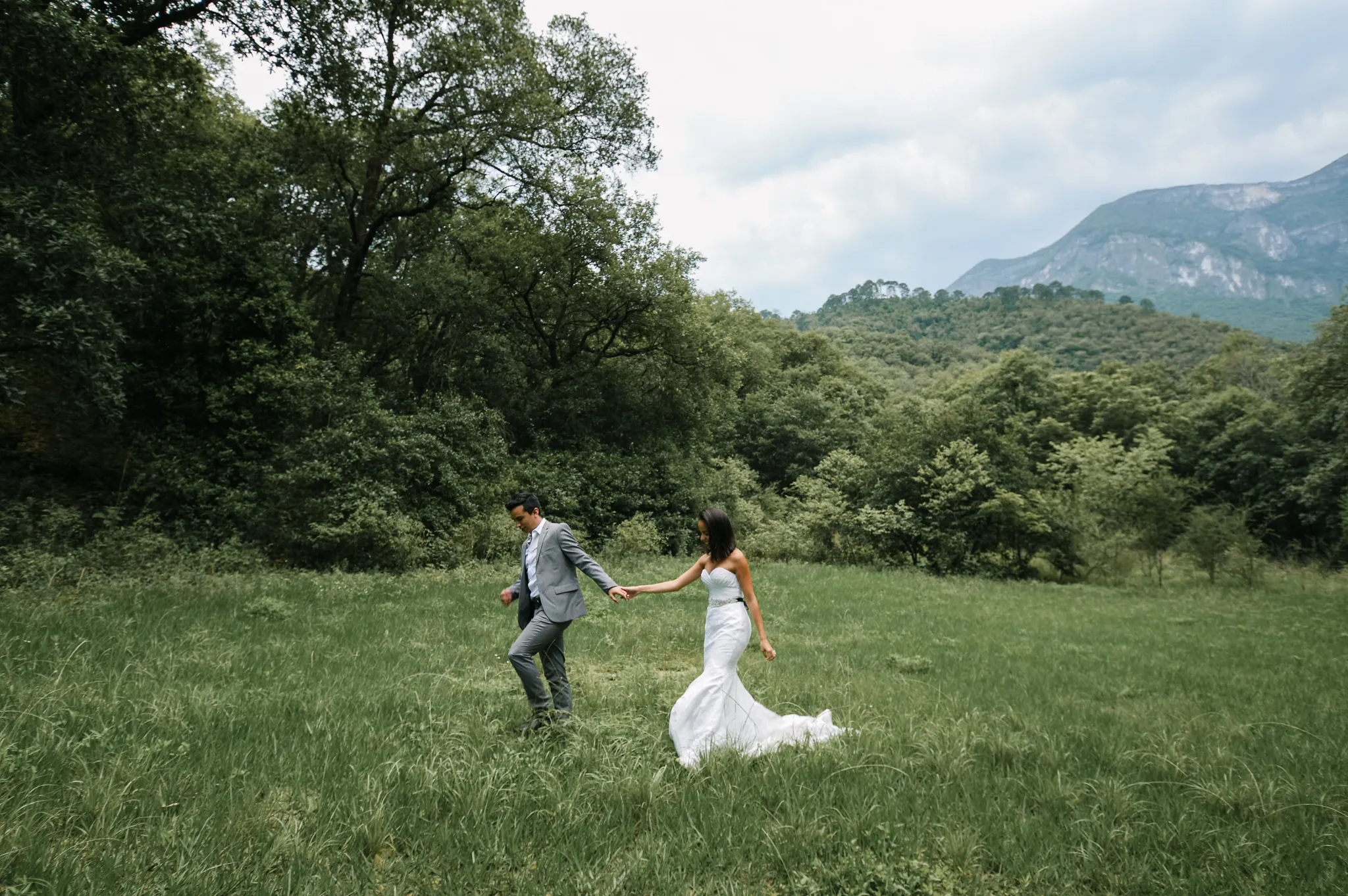 Bride and groom running through an open field during their Texas wedding, photographed by Austin Texas wedding photographer Moments By Marcela