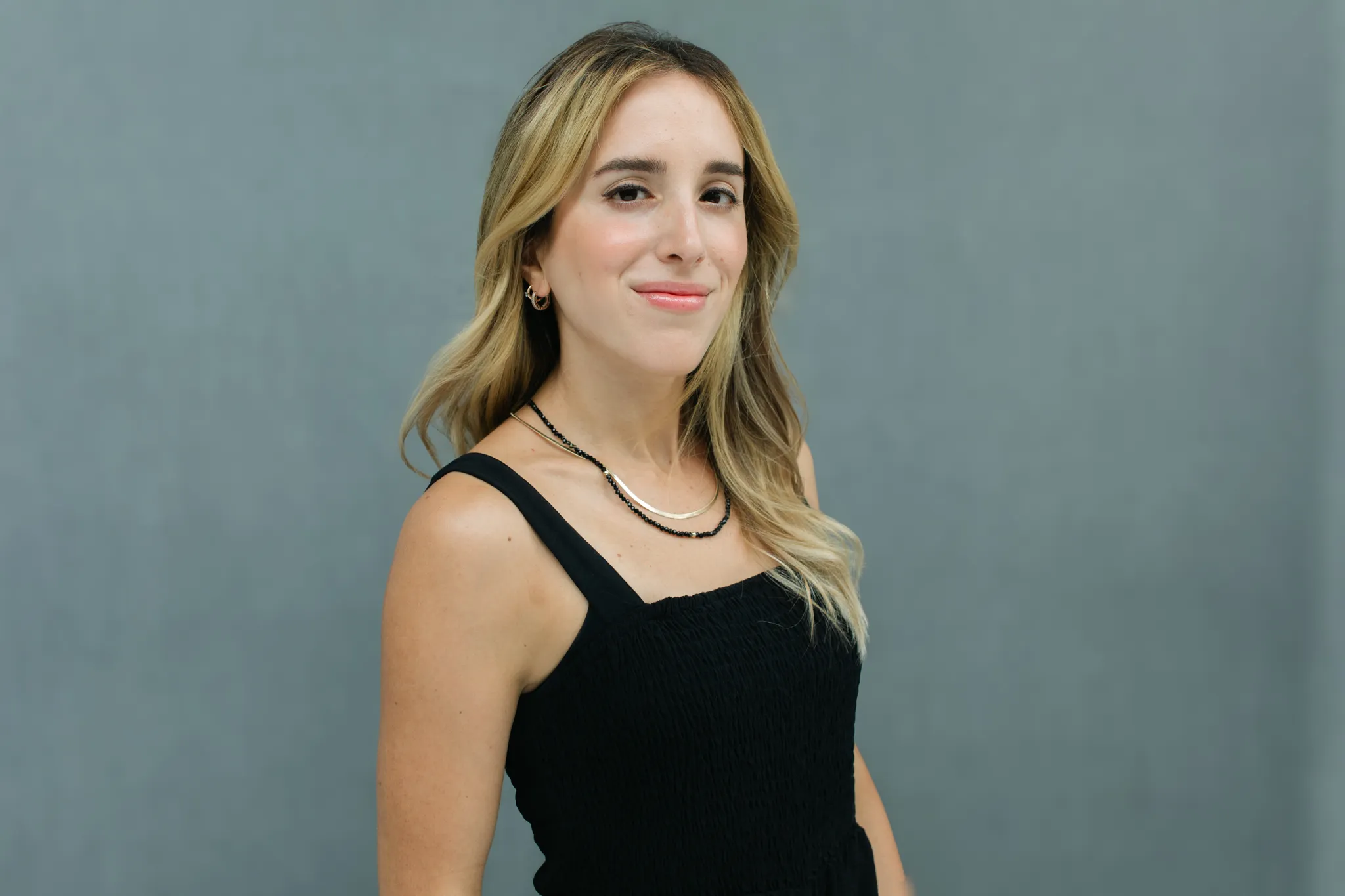 Marcela Briere Austin Texas wedding photographer portrait in black top against a gray background