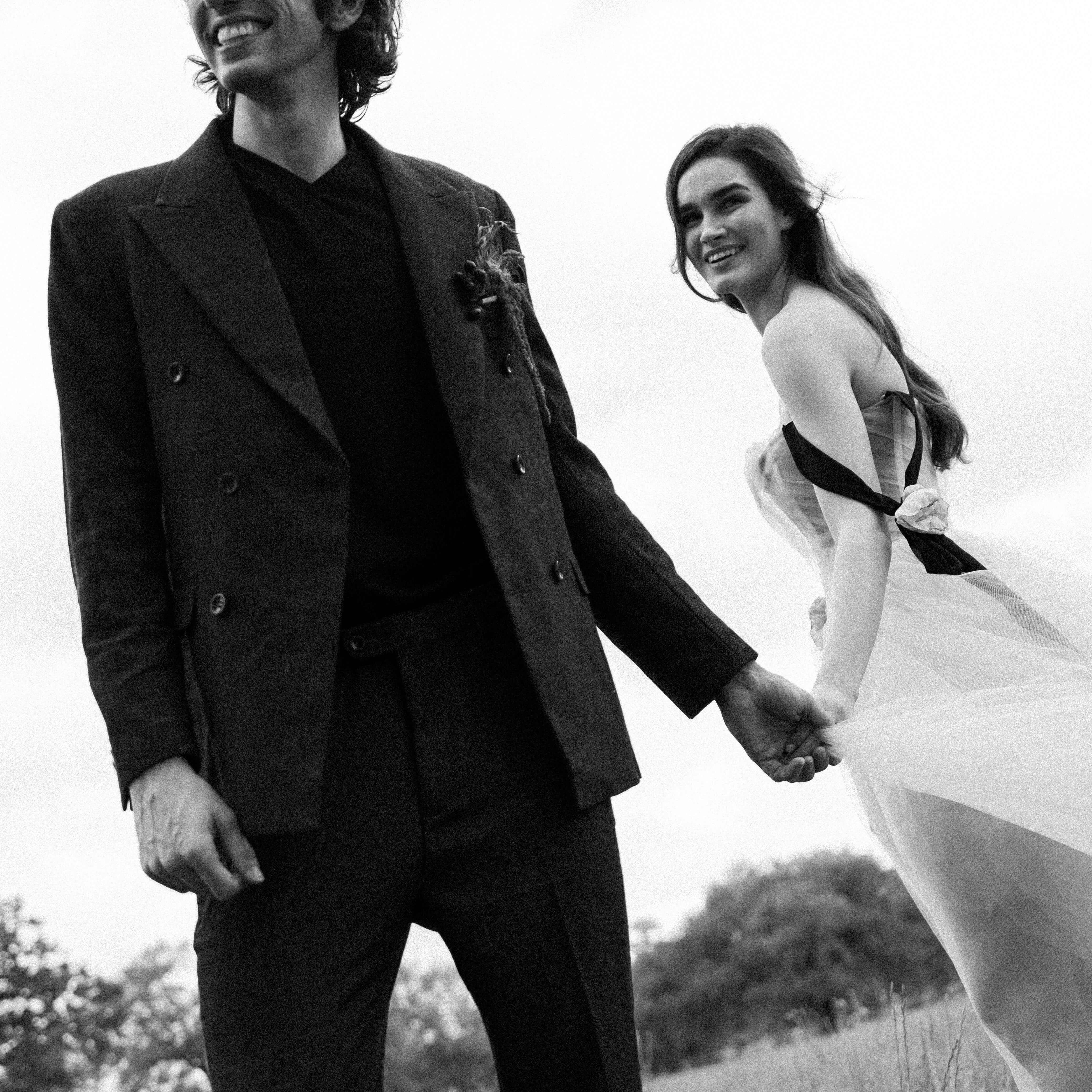 Austin Texas wedding photographer black and white image of two grooms in tuxedos walking through a cactus garden