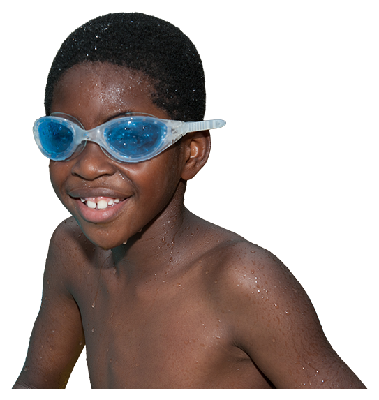 Smiling young boy camper wearing blue swimming goggles and wet from swimming at Camp Dogwood