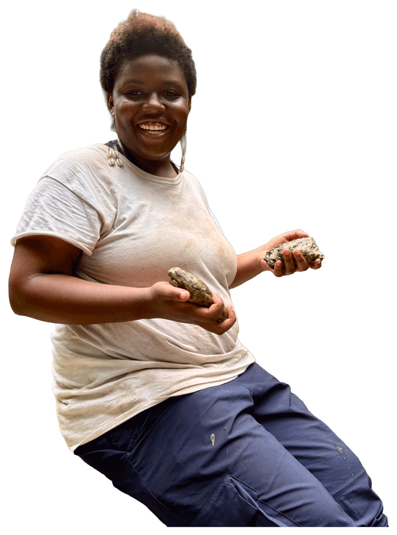 Smiling camper wearing a white t-shirt and blue pants, holding rocks in both hands.