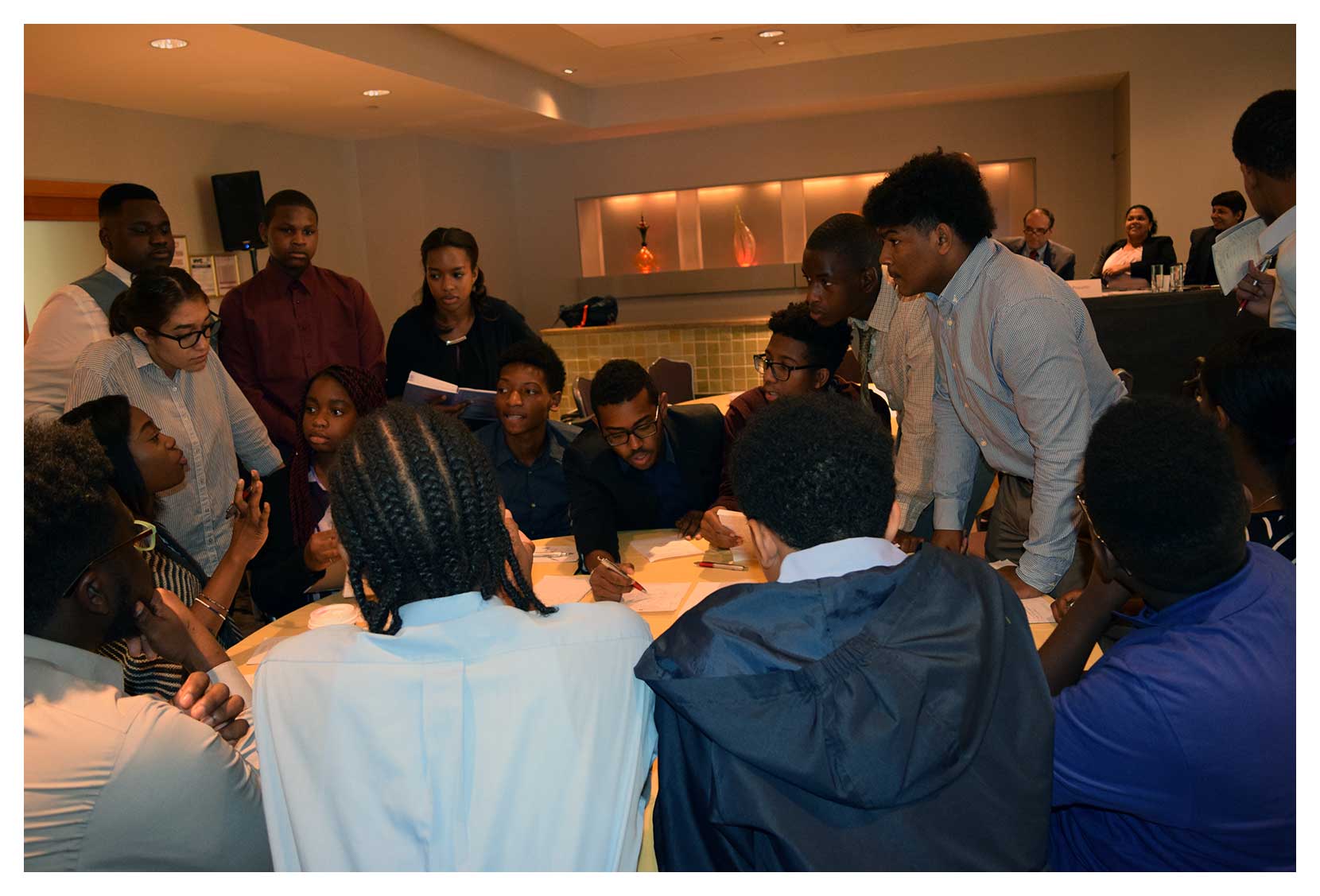 Group of young people in the SAIL program gathered around a table actively discussing and collaborating in a meeting room.