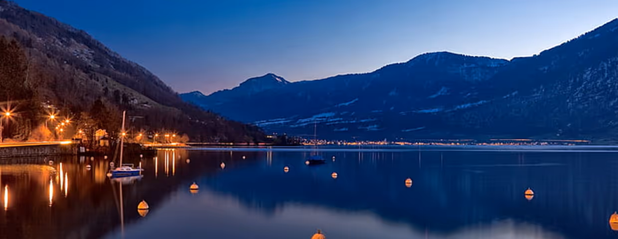 High-quality scenic nighttime photography of a Swiss lake and mountains, emphasizing "Made in Switzerland."