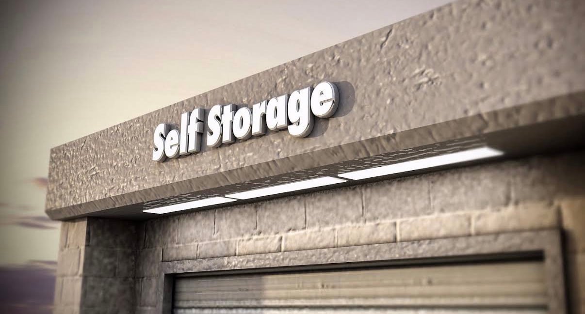 Close-up of a building facade with textured stone and a lit sign reading 'Self Storage'.