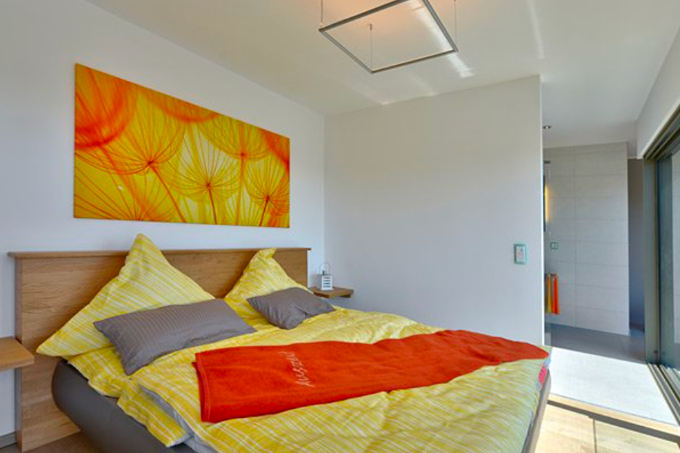 Bungalow mit Flachdach Schlafzimmer in warmem Gelbton mit großem Wandbild und bodentiefen Fenstern