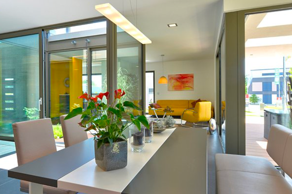 Bungalow mit Flachdach - offener Wohn-Essbereich mit Glasfront und gelbem Küchenblock