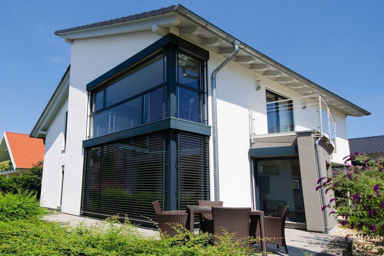 Einfamilienhaus mit Pultdach, großen Fensterfronten, Balkon im Obergeschoss und Terrasse