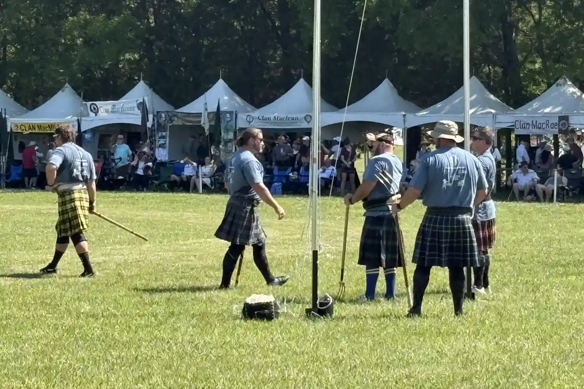 Men in kilts competing in a traditional event at the Loch Norman Highland Games