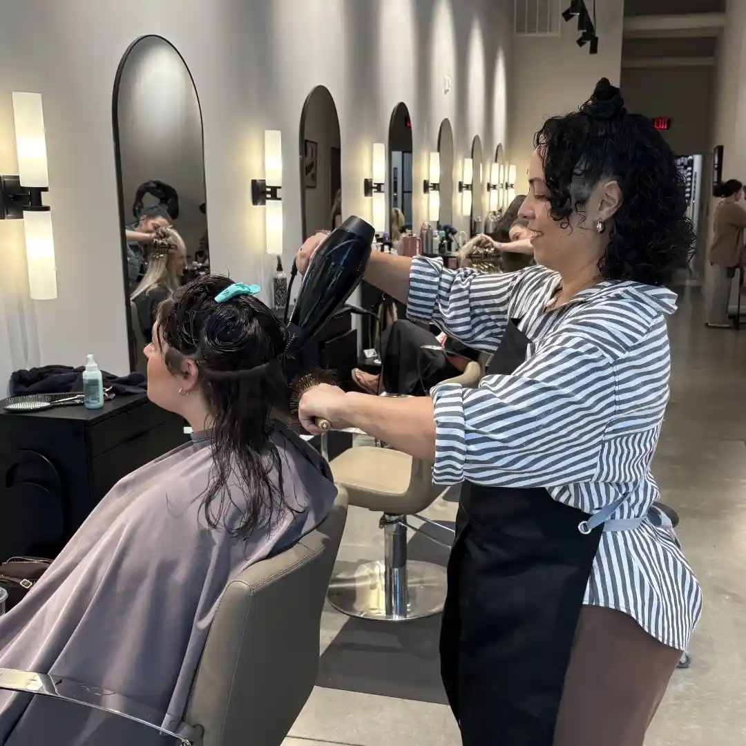 A hairdresser at hair salon in Huntersville cutting and styling her clients' hair