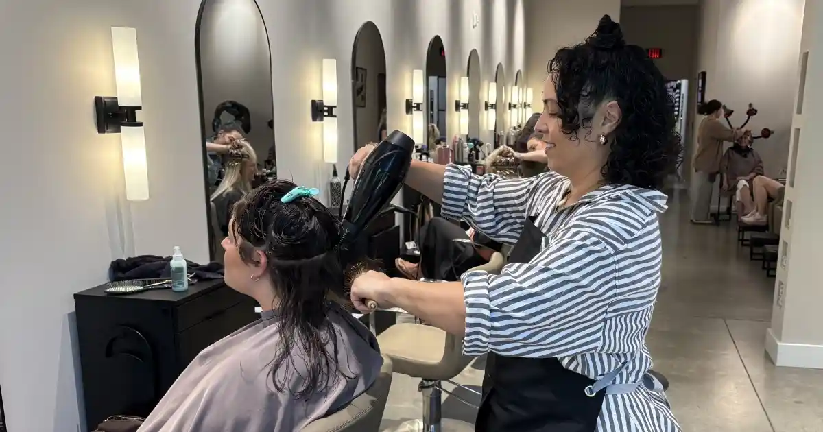 A hairdresser at hair salon in Huntersville cutting and styling her clients' hair