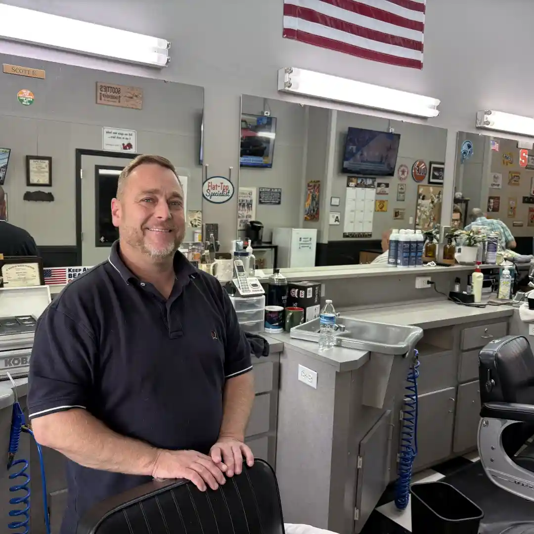 Scott Enloe stands behind his barber's chair at Scottie's Barber Shop