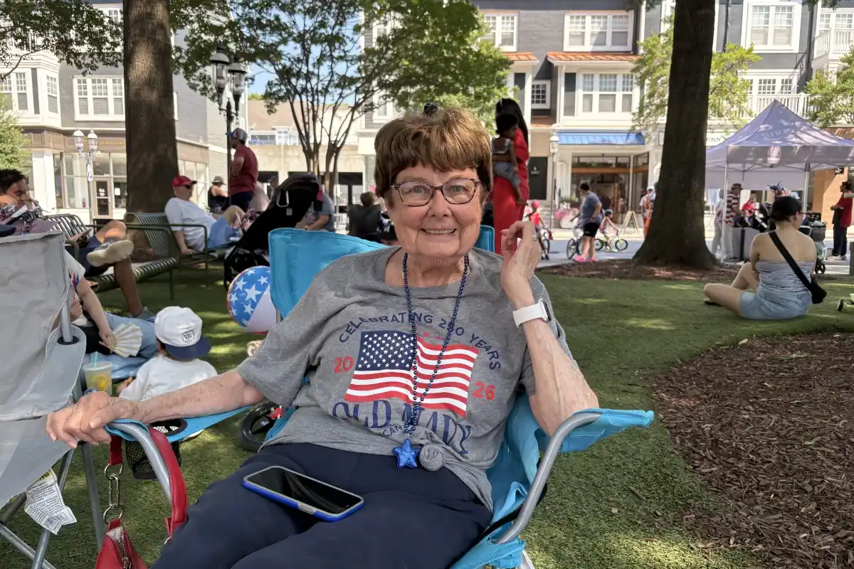 A woman dress in patriotic attire sits in a chair at Birkdale Village waiting for the bike parade