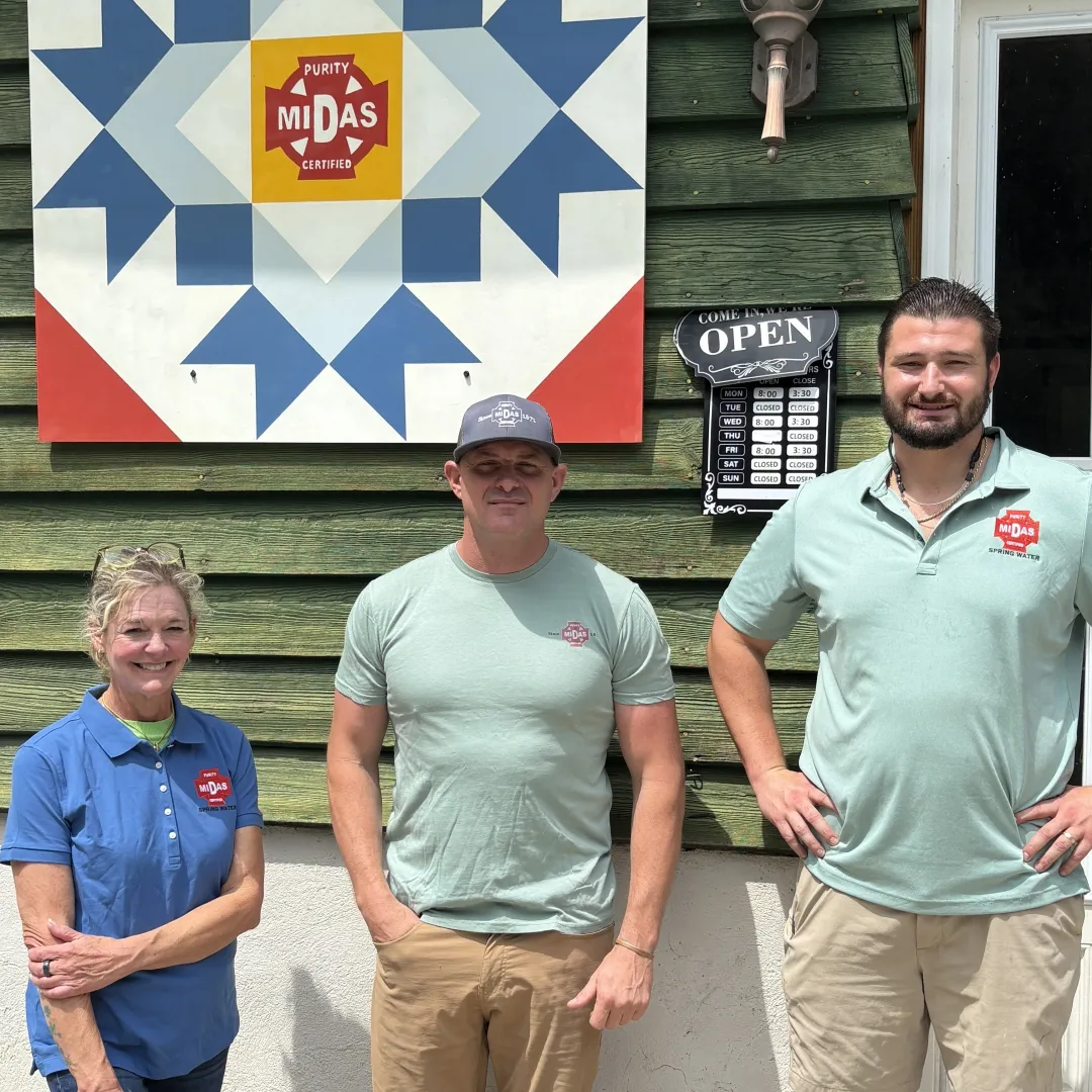 A family of three in Harvest Artisan Cafe shirts stands in front of the menu at Harvest Artisan Cafe