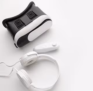 White VR headset with black padding and white over-ear headphones on a white background.