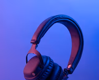 Black over-ear wireless headphones against a purple blue gradient background.