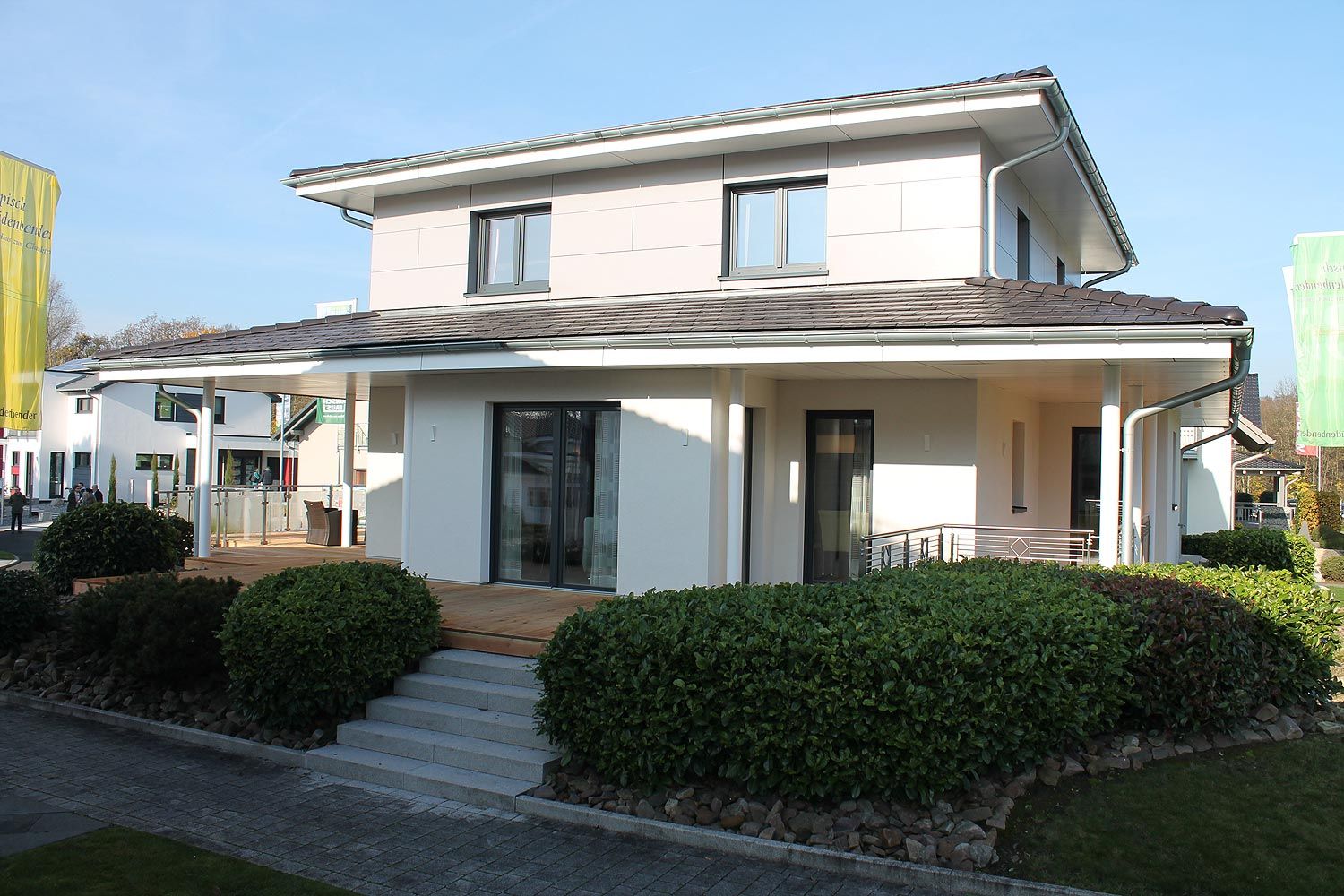 Einfamilienhaus mit Satteldach und überdachter Terrasse, helle Putzfassade mit großen Fensterfronten