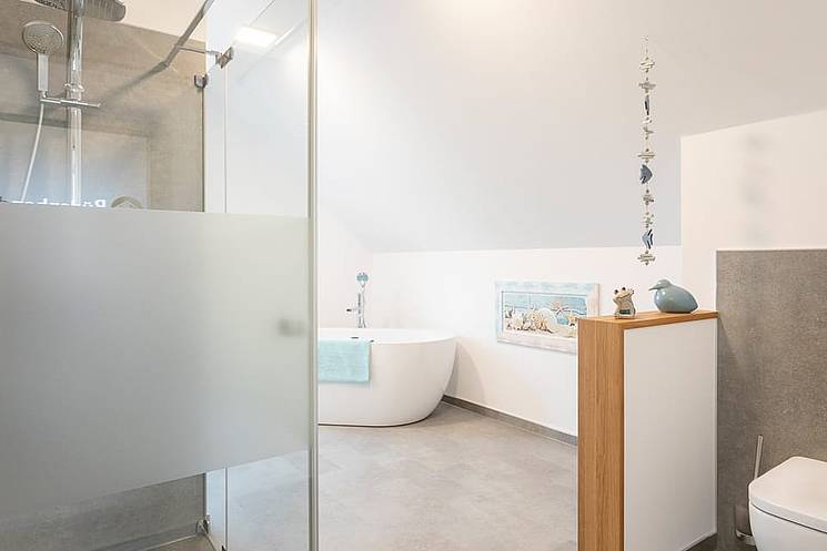 Einfamilienhaus mit Flachdach Badezimmer mit ebenerdiger Dusche freistehender Badewanne und Holzelementen