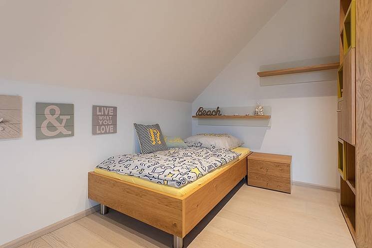 Einfamilienhaus mit Satteldach Schlafzimmer im Dachgeschoss mit Holzmoebeln und Dachschraegen