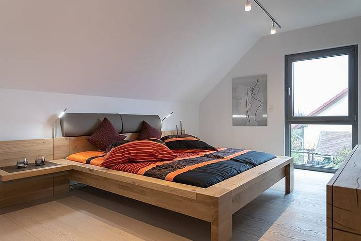Einfamilienhaus mit Satteldach - Schlafzimmer im Dachgeschoss mit Holzbett und Dachschrägen