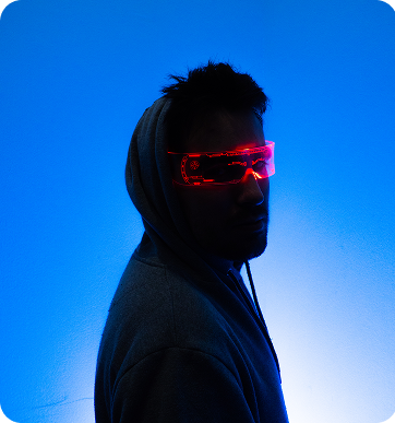 Person wearing a hoodie with futuristic neon red glasses glowing against a blue background.