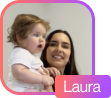 Smiling woman holding a toddler with curly hair against a plain background.