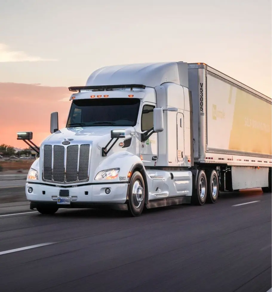 White semi-truck with trailer driving on a highway at sunset.