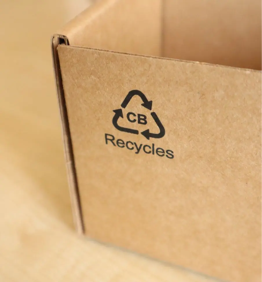 Close-up of a cardboard box corner with a recycling symbol and the letters 'CB' above the word 'Recycles'.