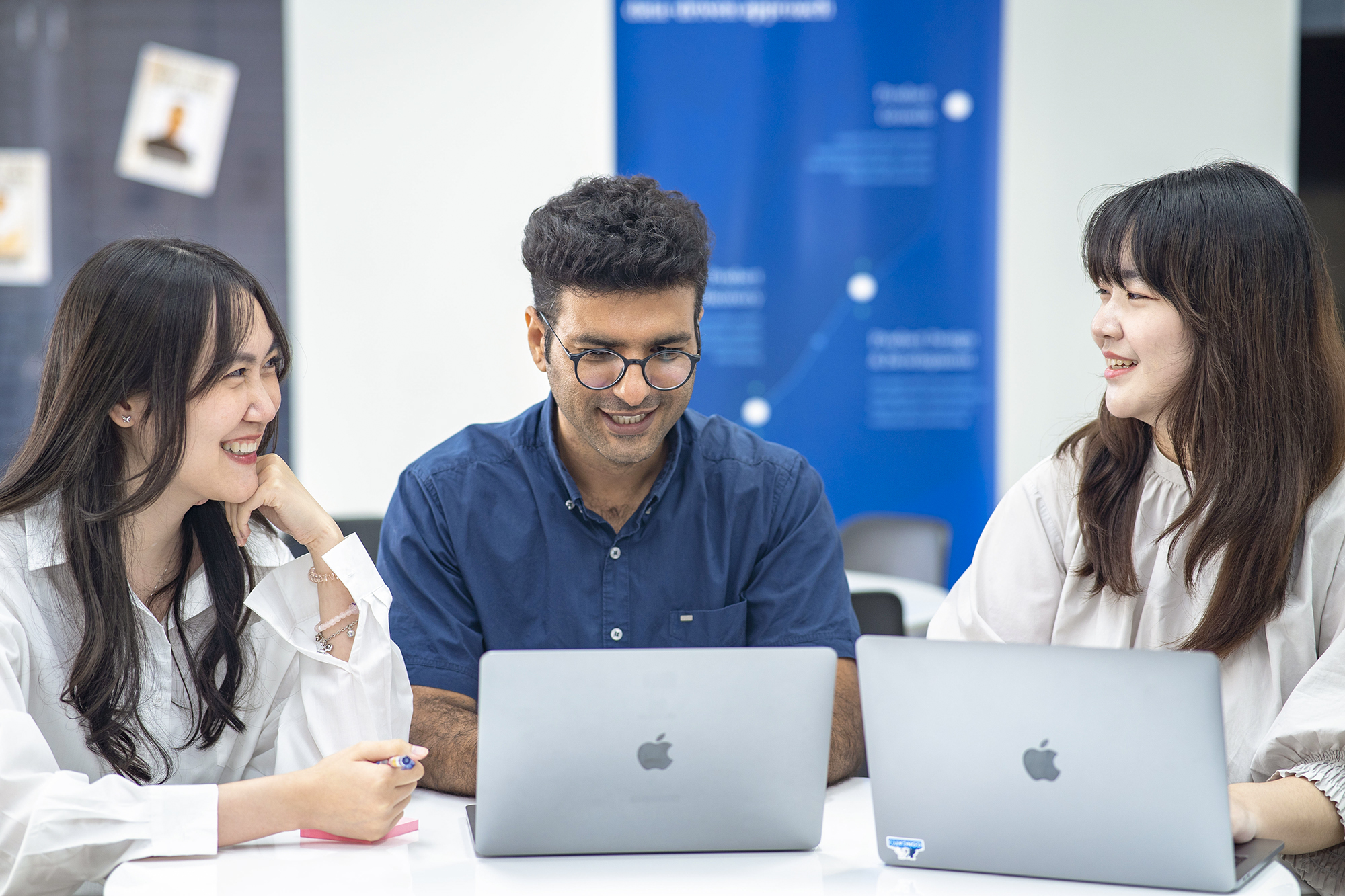 3 personer smiler og jobber sammen rundt en datamaskin