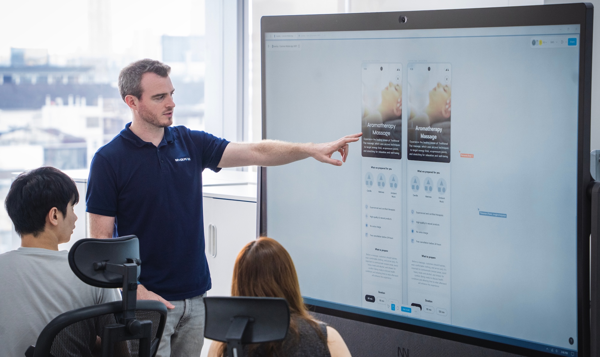 Tre seven peaks ansatte som jobber, en person peker en digital tavle på et digitalt produkt