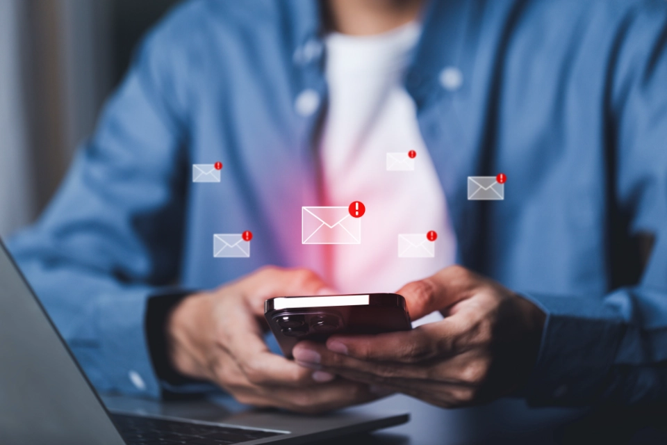 Person hält Smartphone mit mehreren eingeblendeten neuen E-Mail-Benachrichtigungen.