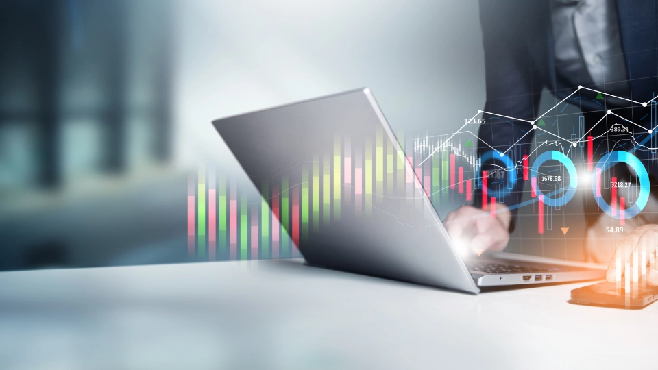 Person arbeitet an einem Laptop mit eingeblendeten digitalen Finanzdiagrammen und Datenvisualisierungen.
