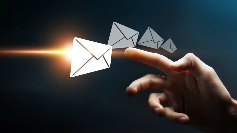 Eine Hand zeigt mit dem Zeigefinger auf eine Reihe von vier stilisierten Briefsymbolen, die von groß zu klein auf dunklem Hintergrund leuchten.