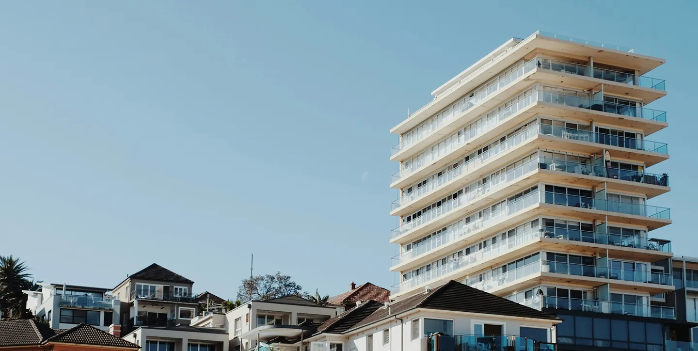 Modern multi-story apartment building with balconies against clear blue sky.