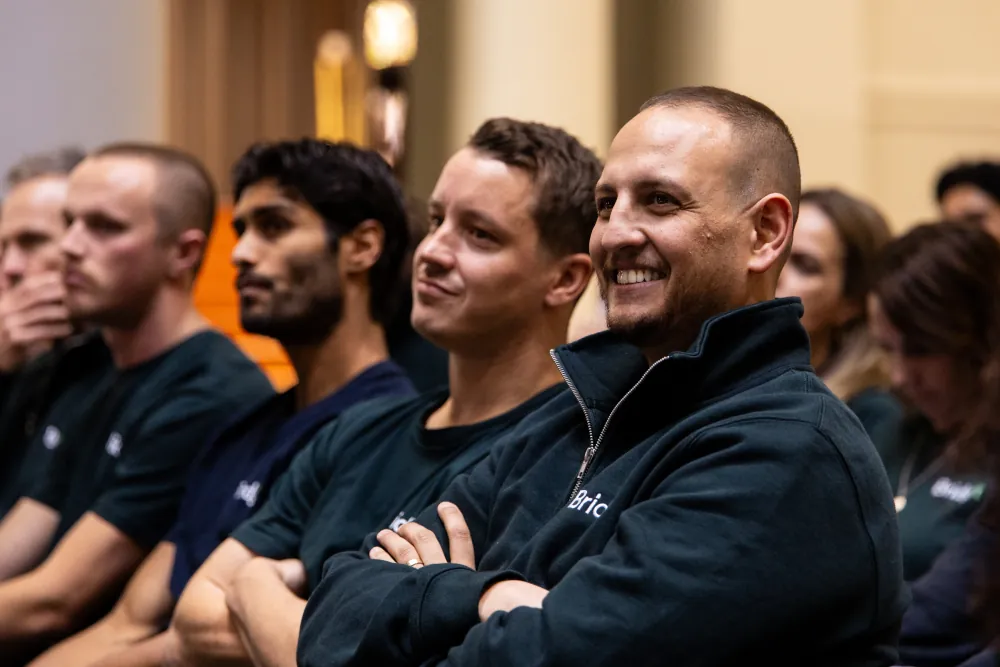 Bridgit team members smiling in the audience at a company event