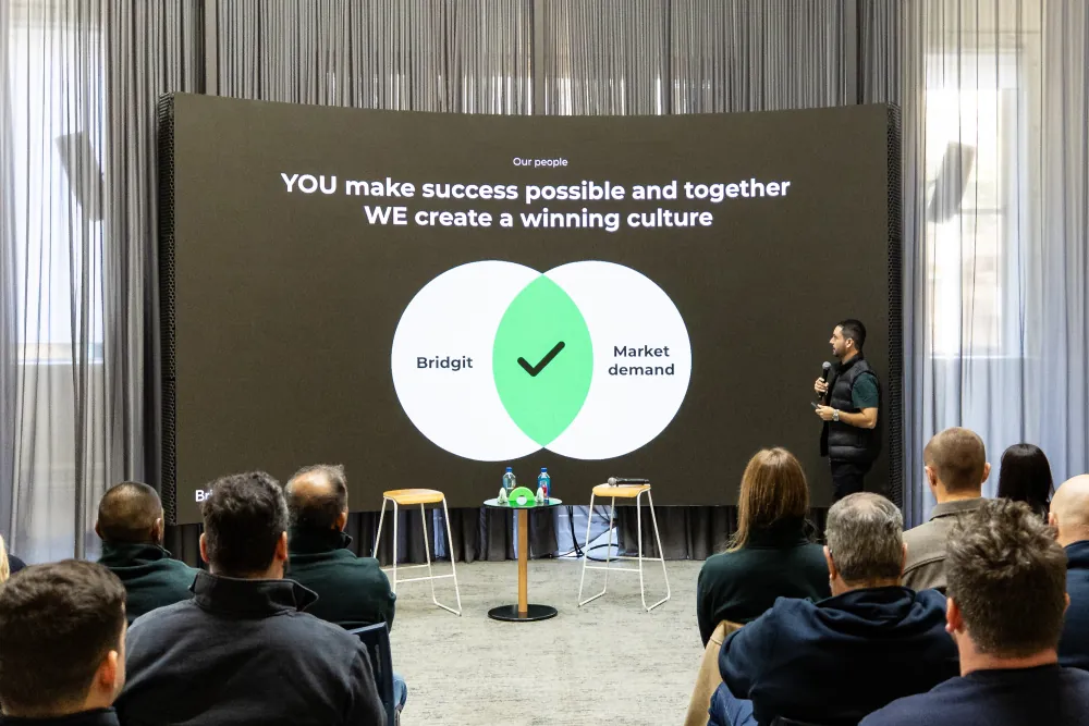 Team members watching a culture session on a large screen
